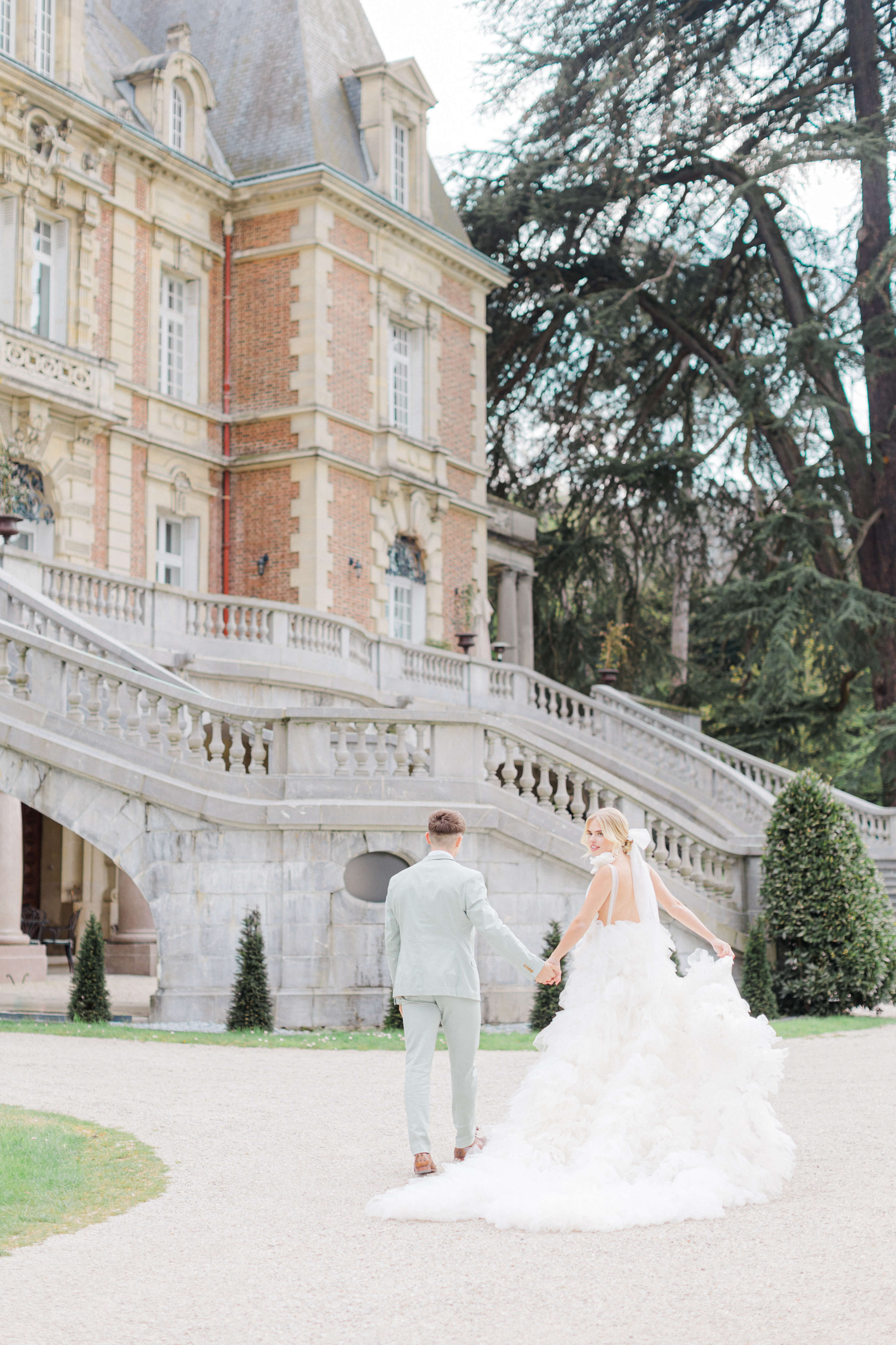 bride and groom walking in front of Chateau Bouffemont in Paris. 