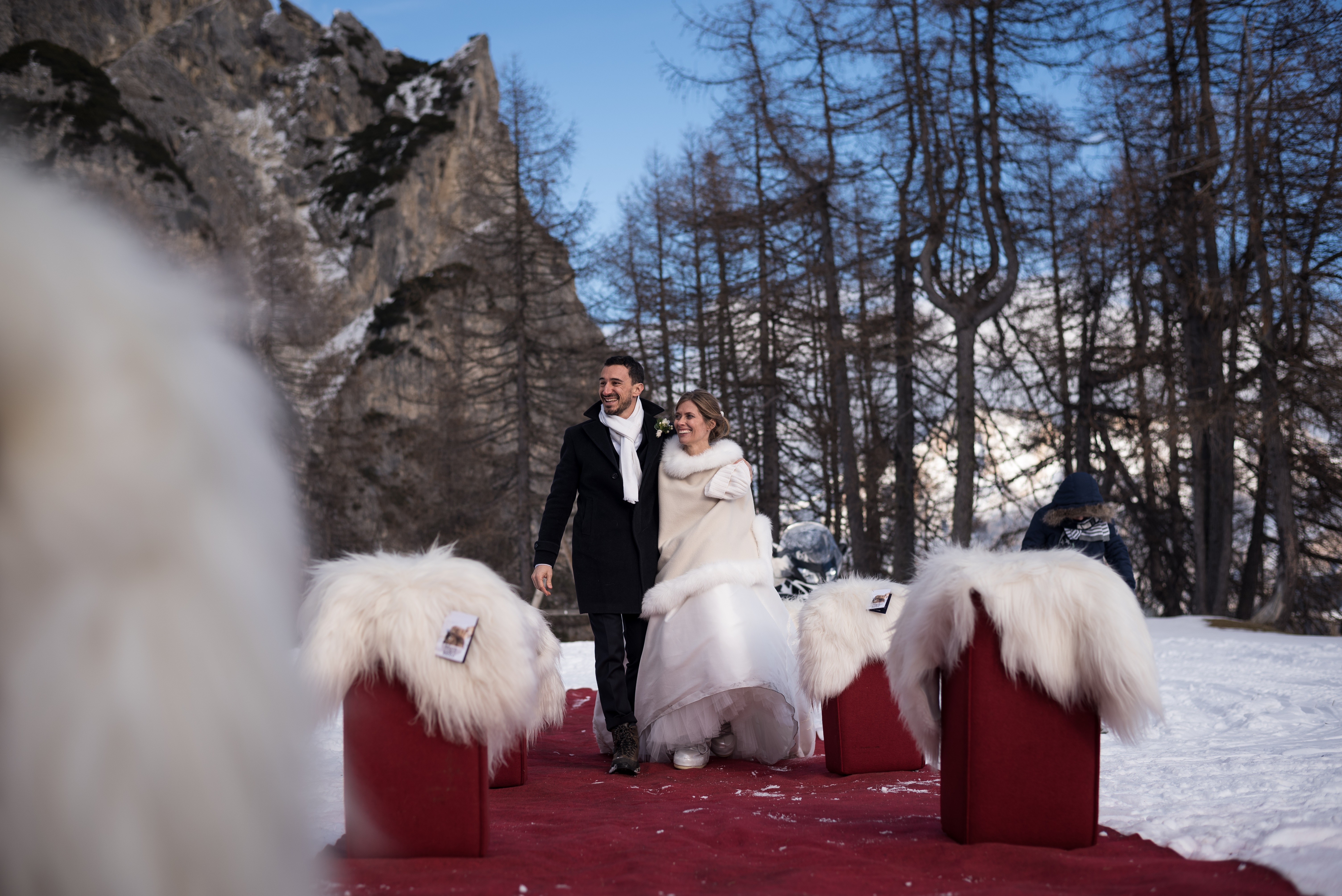 bride and groom walking down a red carpet aisle in snow mountains