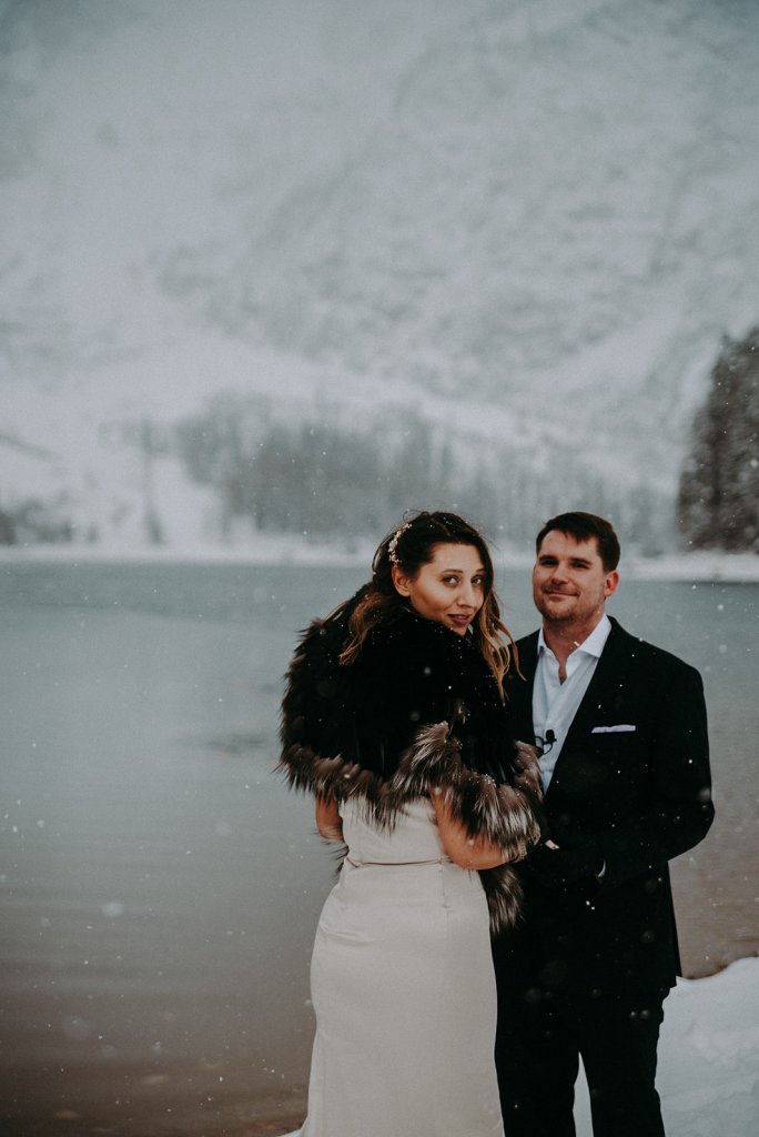  bride and groom looking at camera at a snowy lake ceremony