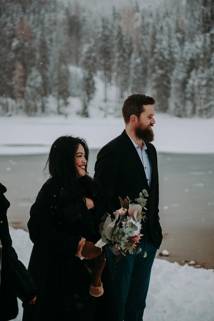 bridal party dresses in black a snowy lake ceremony, bridesmaid holding a bouquet