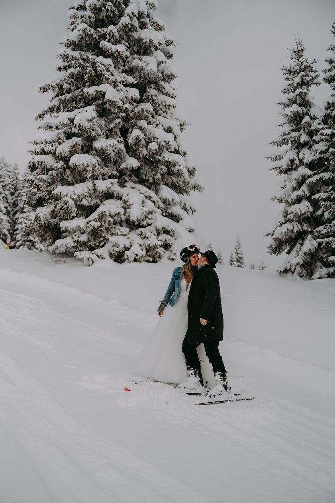 bride and groom ikissing while wearing ski in snow mountains