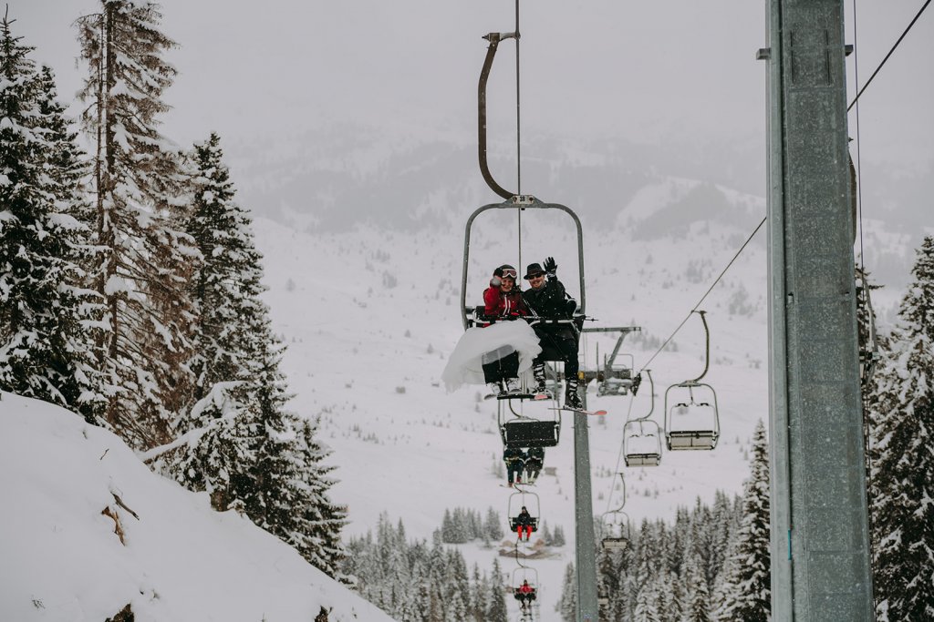 bride and groom in a chairlift in snow mountains