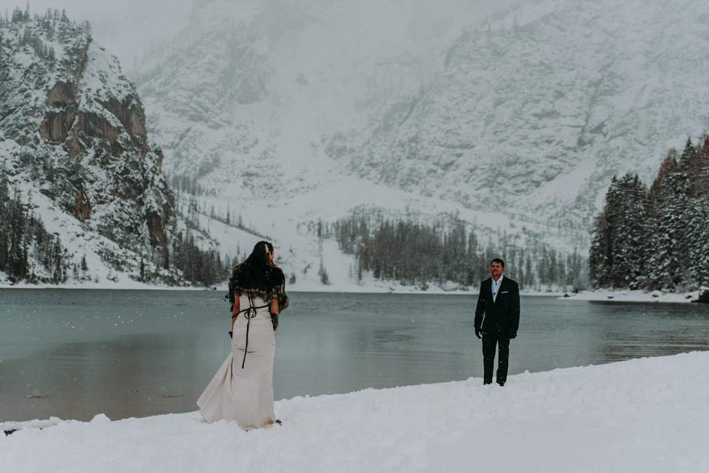  bride and groom walking towards each other at a snowy lake ceremony