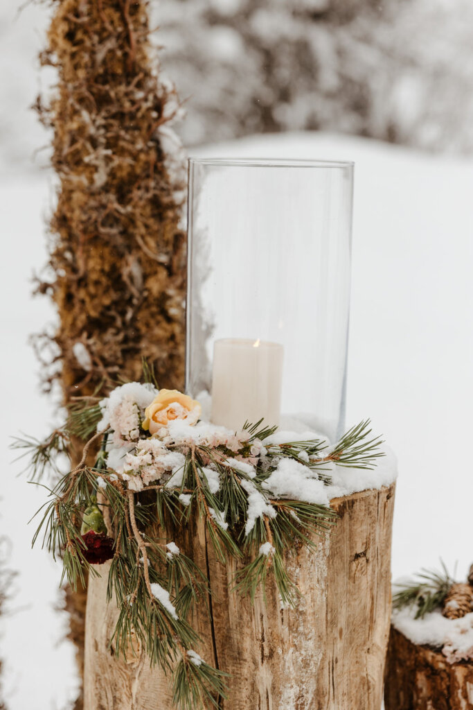 pillar candle on glass hurricane candle holder on tree chop for winter wedding outdoors on snow