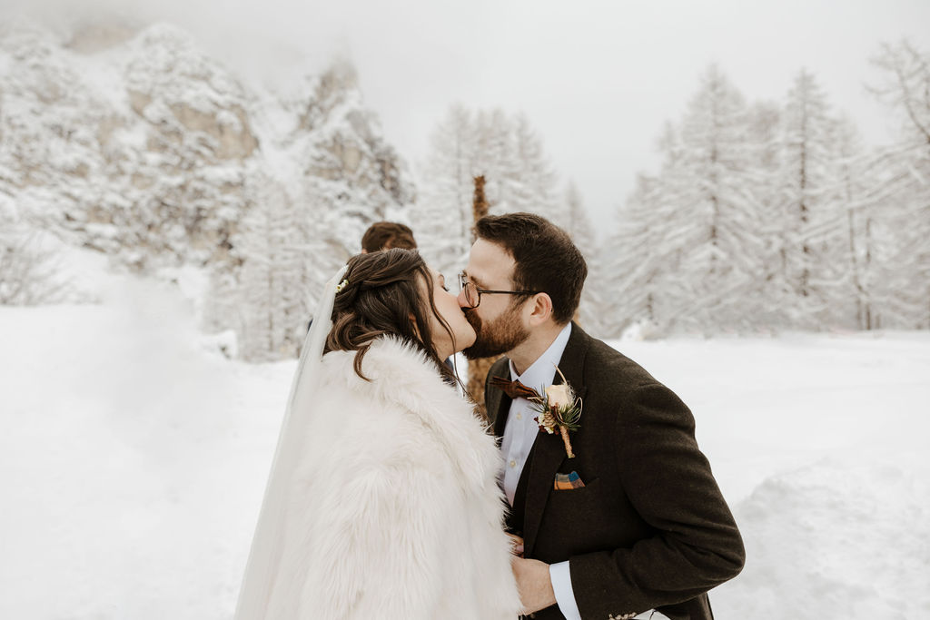 newlywed bride and groom kissing-  winter wedding ideas ceremony on the snow
