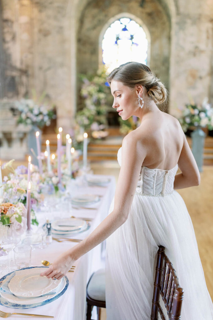 blonde bride checking her wedding menu at her reception table and smiling. she's wearing a sweetheart dress