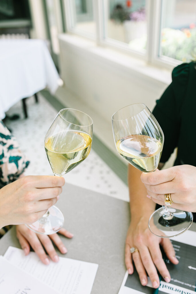 2 girls hands toasting with 2 glasses of white wine for girl engagement