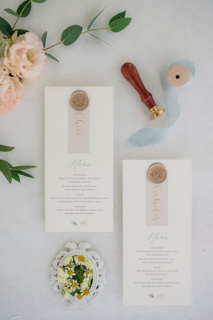  Lake Como wedding planner - flatlay of bespoke wedding menus with calligraphy, wax seals, flowers, wax stamp and place cards