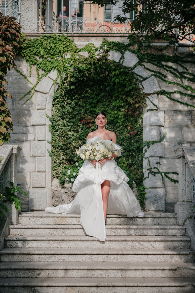  Lake Como wedding planner Villa Cipressi garden steps bride walking down to ceremony spot holding bouquet. an arch in the backgroun d